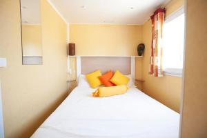 a small bedroom with a bed with yellow and orange pillows at Sunny Tiny House with Sea view in Roque