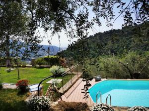 a swimming pool with a wooden deck next to a yard at Agriturismo C'era Una Volta in Camporosso