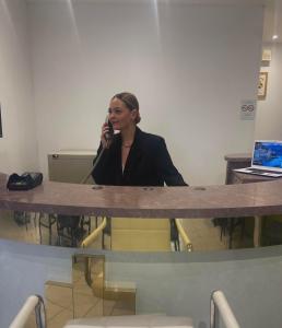 a woman sitting at a table talking on a cell phone at Hôtel du Cerf in La Guerche-sur-lʼAubois