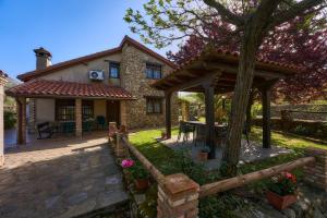 una casa de piedra con una mesa y un pabellón en La Cañada del Valle del Jerte, en Navaconcejo