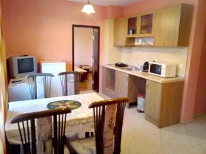 a kitchen with a table and chairs and a microwave at Семеен хотел Бостън in Ravda