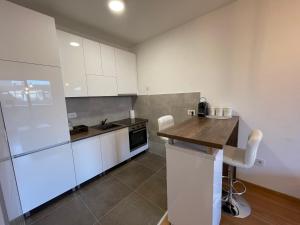 a kitchen with white cabinets and a wooden counter top at Fantastic centar Novi Sad in Novi Sad