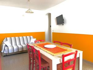 - une table à manger avec des chaises rouges et un canapé dans l'établissement Casa Ada, à Leuca