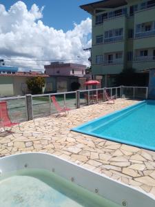 a swimming pool with chairs and a building at Pousada Campo Verde in Guarapari