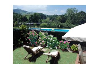 un patio con 2 sillas y flores y una piscina en Descanso en el Sella, en Cangas de Onís