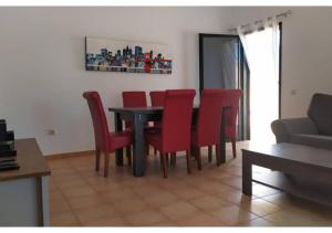 ein Esszimmer mit einem Tisch und roten Stühlen in der Unterkunft Anahi Homes Corralejo- Villa Dracacena 14 in La Oliva