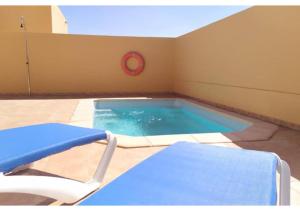 einen Pool mit einem Stuhl und einem roten Frisbee in der Unterkunft Anahi Homes Corralejo- Villa Dracacena 14 in La Oliva