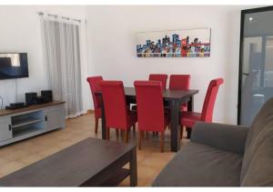 a living room with a dining room table and red chairs at Anahi Homes Corralejo- Villa Dracacena 14 in La Oliva