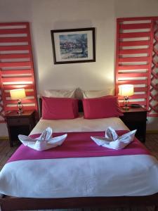 a bedroom with a large bed with two white pillows at Hotel Des Neiges in Cilaos