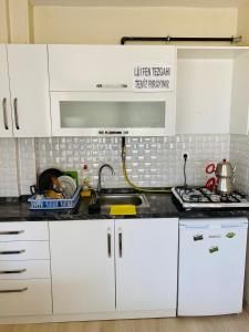 uma cozinha com armários brancos e um lavatório em TANER PANSiYON em Edirne