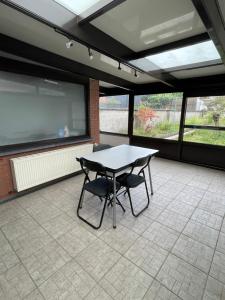 a table and two chairs in a room with a large screen at Maison Pétria in Fontaine-lʼÉvêque