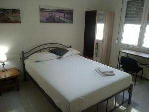 a bedroom with a bed and a desk and two windows at Room to rent-shared wc in Kavála