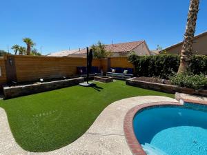 un patio trasero con césped y piscina en Gorgeous Henderson Home with Pool! en Las Vegas