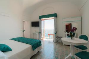 a bedroom with a bed and a table and a window at Villa Nettuno in Positano