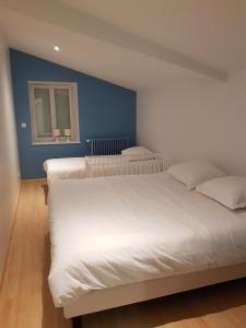 1 dormitorio con 2 camas blancas y pared azul en La Mollerie, en Saint-Bonnet-de-Cray