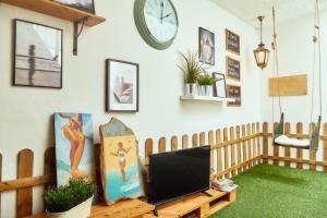 a living room with a tv and a clock on the wall at Balili Surf House in Baleal