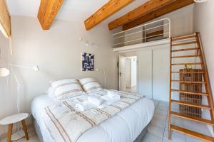 a bedroom with a white bed and a wooden ladder at A LA CALANQUE - Jolie Maison en bord de mer in Marseille