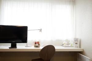 a television sitting on a desk in front of a window at Brit Hôtel Dinan - Taden in Dinan