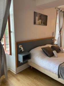 a bedroom with a bed with a night stand next to a window at Hôtel du Cerf in La Guerche-sur-lʼAubois