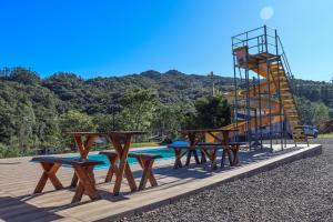 a group of picnic tables and a ladder next to a pool at Pousada e sítio do Robinho in Timbe do Sul