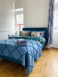 um quarto com uma cama azul e uma janela em Spacious 3BR, town centre, 8 min walk to beach em Bournemouth