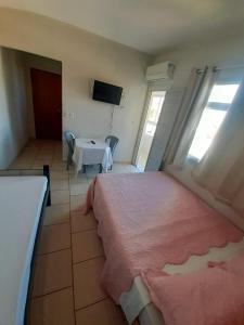 a bedroom with a bed and a table and a television at Pousada Campo Verde in Guarapari