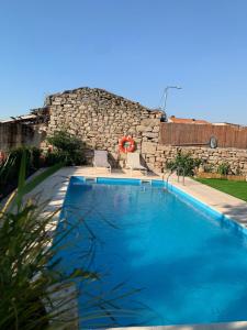 a large blue swimming pool next to a stone wall at Villa Candoso in Candoso