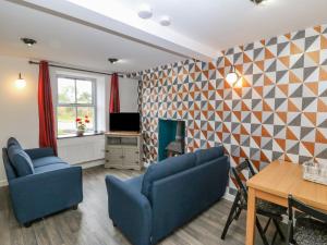 a living room with two blue chairs and a table at Dwyros in Pwllheli