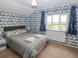 a bedroom with a bed with blue and white wallpaper at Dwyros in Pwllheli