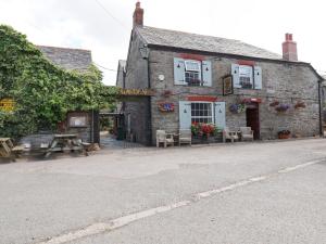 an old brick building with tables and chairs in front of it at Gwynn Cottage in Bodmin
