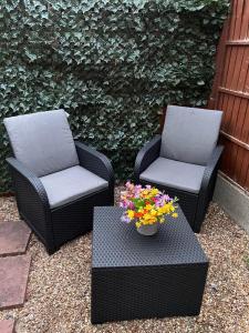 two chairs and a table with flowers on a patio at Stunning Newly Decorated One bedroom flat with own entrance and garden in London