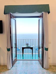 a large glass door leading to a balcony with a table at Villa Nettuno in Positano