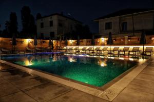 a swimming pool with chairs and a building at night at Bujtina SIAR in Pogradec
