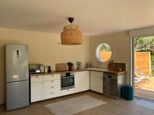 uma cozinha com armários brancos e um frigorífico de aço inoxidável em Biby BeachHouse em Lacanau