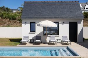 a patio with chairs and an umbrella next to a pool at La Maison des Embruns in Plouarzel