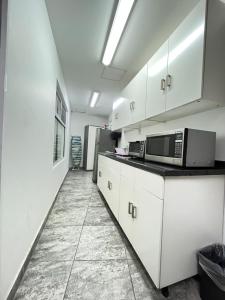 La cuisine est équipée de placards blancs et d'un four micro-ondes. dans l'établissement Genesis Suites / Lofts, à San Luis Potosí