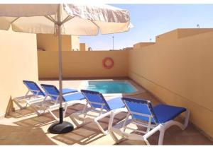 een groep stoelen en een parasol naast een zwembad bij Anahi Homes Corralejo- Bicacarera 9 in La Oliva