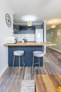 une cuisine avec deux tabourets de bar et un comptoir dans l'établissement Queen Street Apartments, à Whitehaven