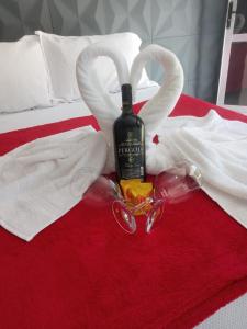 a bottle of wine and a pair of glasses on a bed at LUZ DO LUAR in Pedra Azul