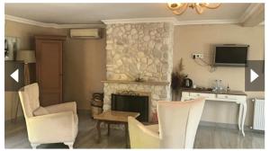 a living room with a stone fireplace and white chairs at Alesta Butik Otel in Şile