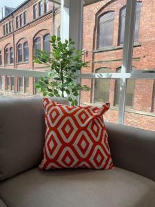 a pillow sitting on a couch in front of a window at Central Leeds townhouse with private roof garden Sleeps 4 in Leeds