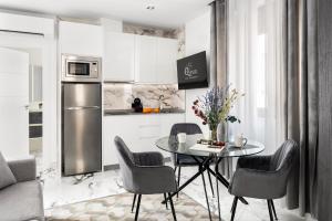 cocina con mesa, sillas y nevera en Quivir Apartamentos Deluxe Casa del Arco en Andújar