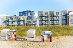 クックスハーフェンにあるBeach Lodge BL03の建物前の砂浜に四脚のビーチチェア