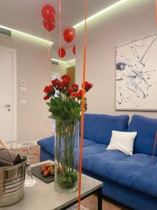 Light Hotel في تيرانا: غرفة معيشة مع أريكة زرقاء و مزهرية مع ورود حمراء