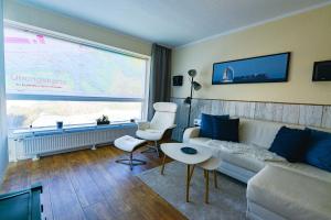 uma sala de estar com um sofá branco e uma grande janela em Haus Frische Brise 1210 em Cuxhaven