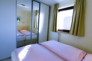 a small bedroom with two beds and a mirror at Strandhochhaus SD06 in Cuxhaven