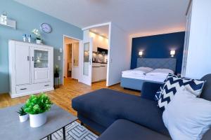 a living room with a blue couch and a bedroom at Strandhochhaus SHC2 in Cuxhaven