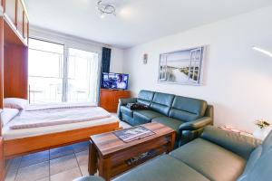 uma sala de estar com um sofá, uma cama e uma mesa em Haus Horizont H14B em Cuxhaven