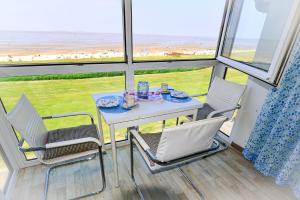 a table and chairs in a room with a view of the ocean at Haus Horizont H14B in Cuxhaven