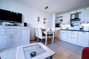 eine große weiße Küche mit einem Tisch und einem TV in der Unterkunft Haus Horizont HZ09 in Cuxhaven